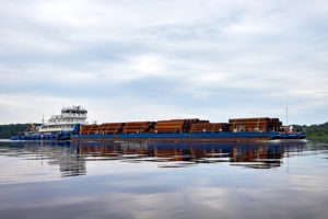 ship pushing barge loaded with drilling pipes