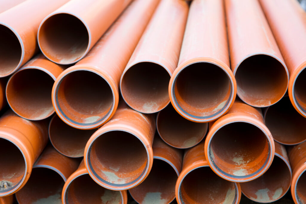 Close-up of steel pipes stacked together, with handling equipment nearby.