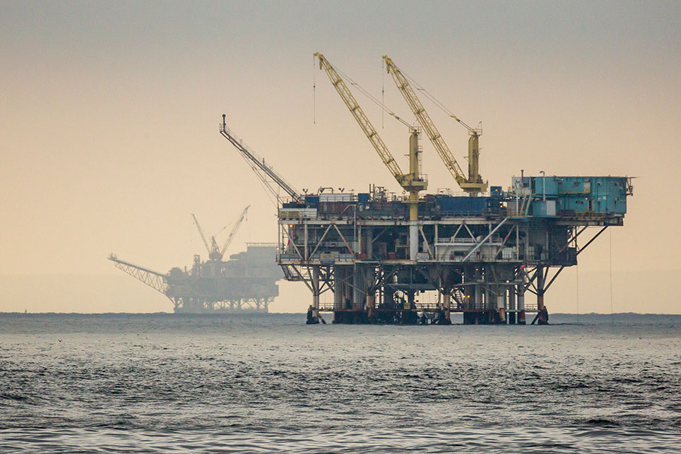 Two offshore oil wells off the coast, highlighting oil rig production against the calm ocean.